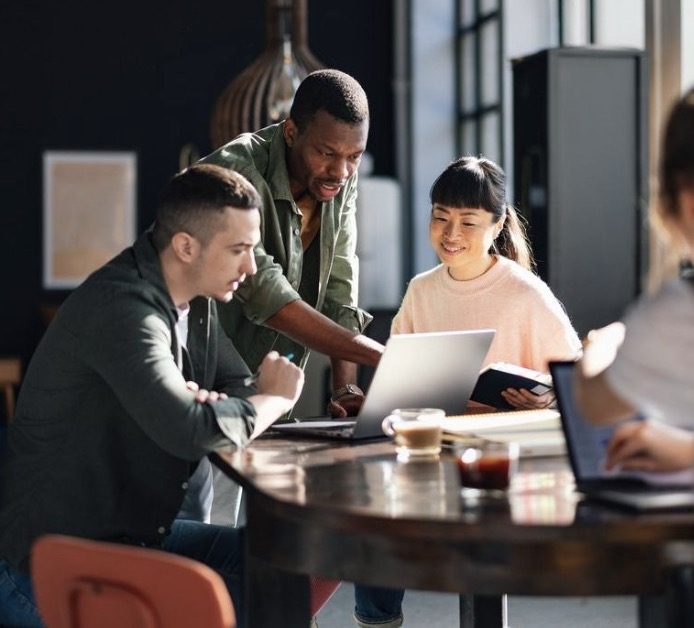 Team collaborating on AI adoption around a laptop